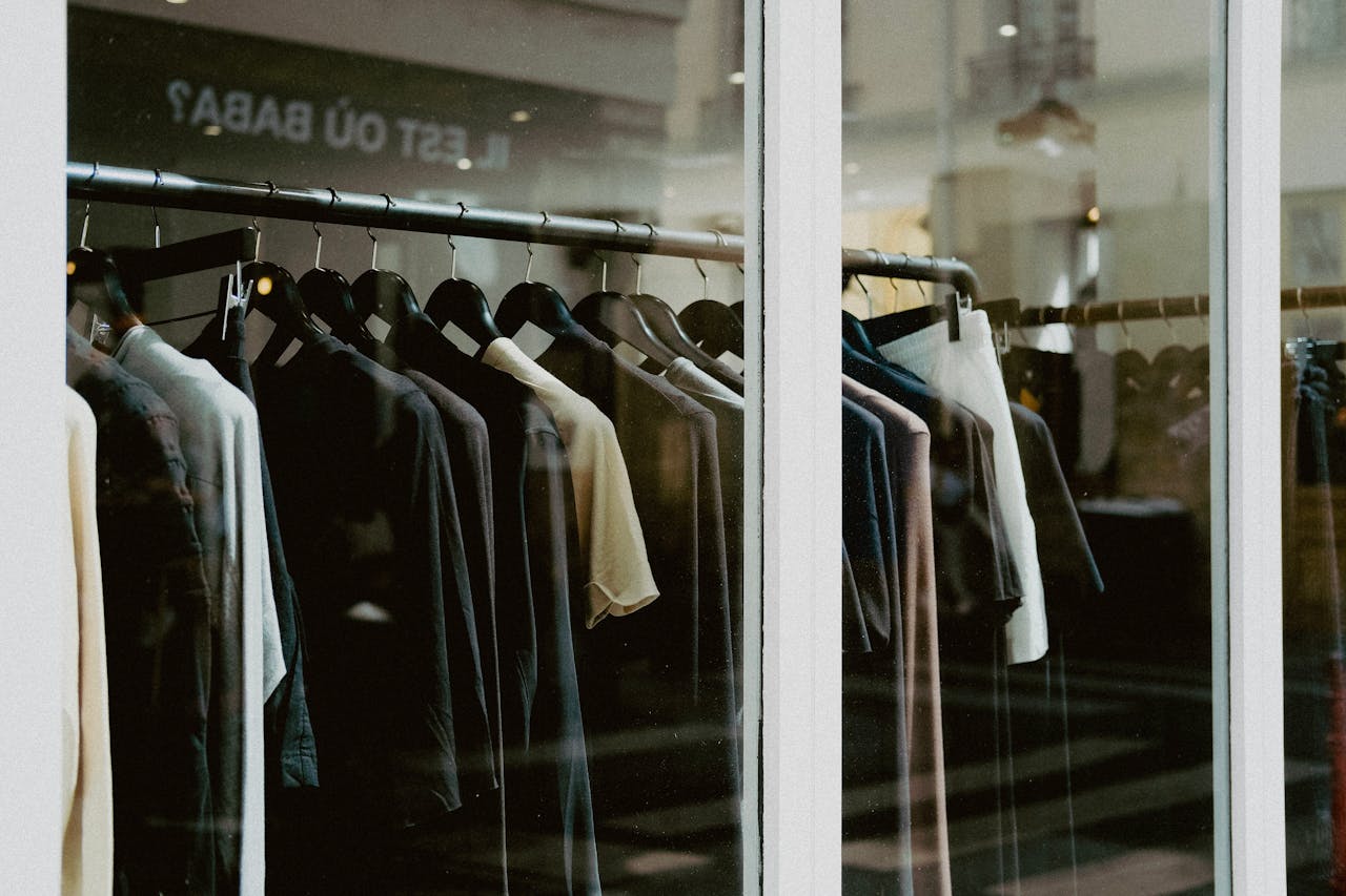 Close-up of clothing on hangers inside a fashion store window.